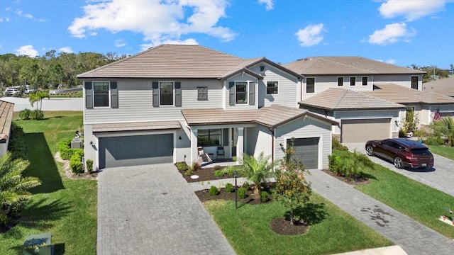 view of front of house featuring decorative driveway, a front lawn, and a tile roof