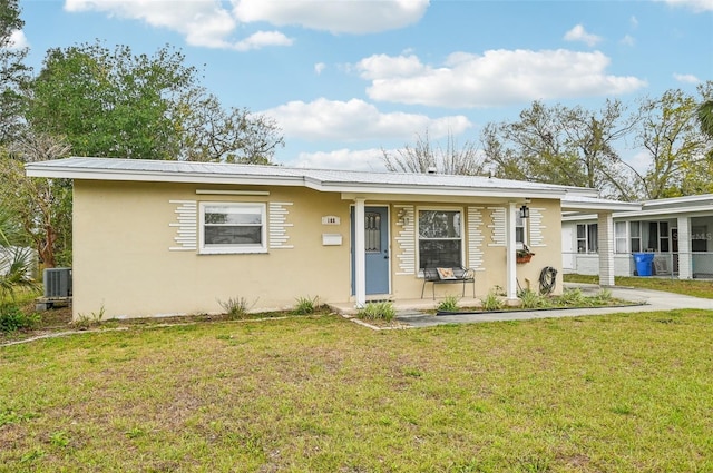 single story home with stucco siding, covered porch, metal roof, and a front lawn