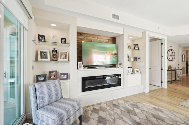 living room featuring wood finished floors, visible vents, and a high end fireplace