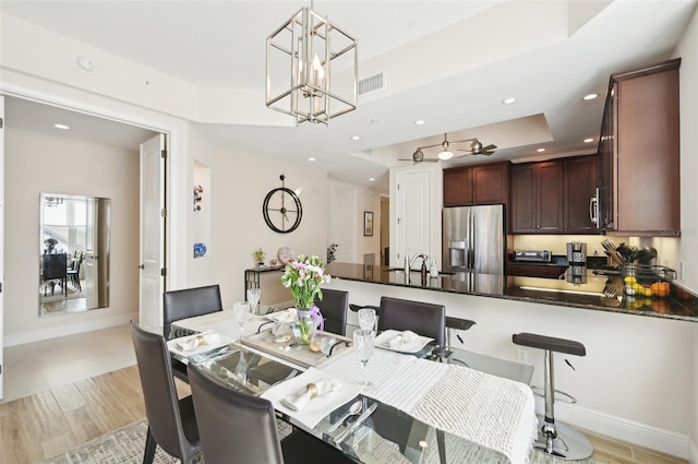 dining area with visible vents, a notable chandelier, a tray ceiling, recessed lighting, and baseboards