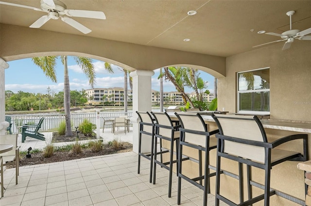 view of patio with outdoor dry bar, ceiling fan, and fence