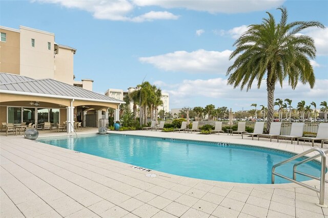 pool with a patio, fence, and ceiling fan