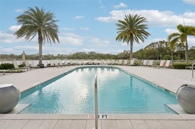 community pool with a patio area and fence