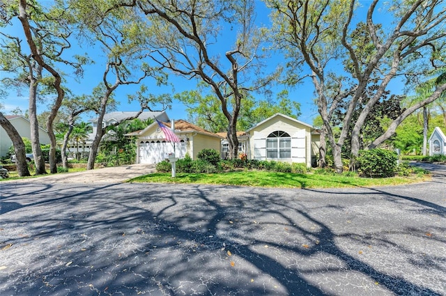 view of front of property featuring aphalt driveway, a front lawn, and a garage