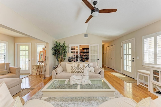 living room featuring visible vents, baseboards, ceiling fan, vaulted ceiling, and light wood-style flooring