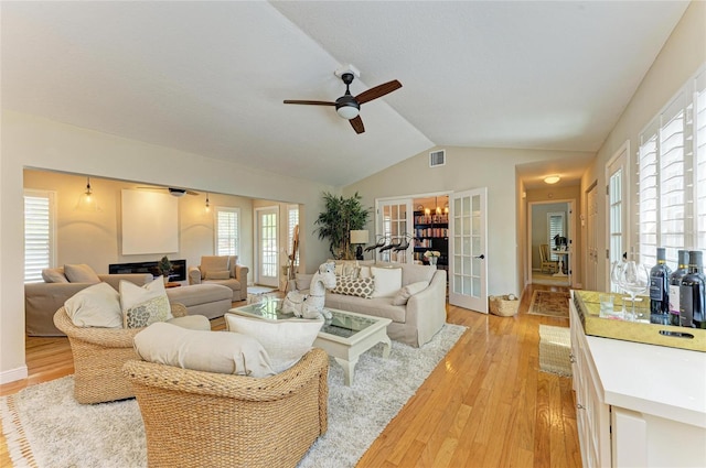 living area with visible vents, lofted ceiling, ceiling fan, french doors, and light wood-type flooring