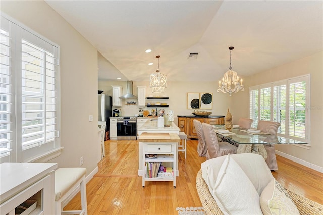 dining area with visible vents, baseboards, a notable chandelier, and light wood finished floors