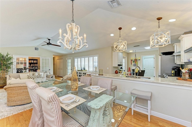 dining space with lofted ceiling, visible vents, and light wood finished floors