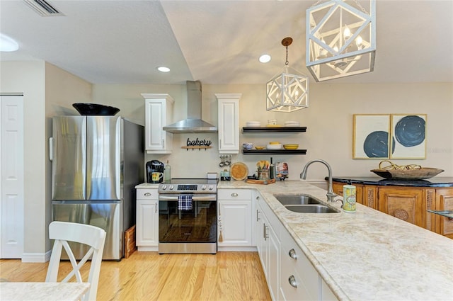 kitchen with visible vents, light wood-style flooring, a sink, appliances with stainless steel finishes, and wall chimney exhaust hood