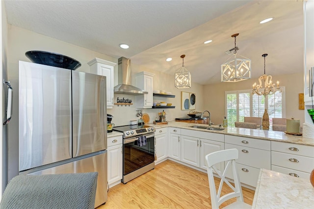 kitchen with an inviting chandelier, a sink, stainless steel appliances, wall chimney exhaust hood, and light wood-type flooring