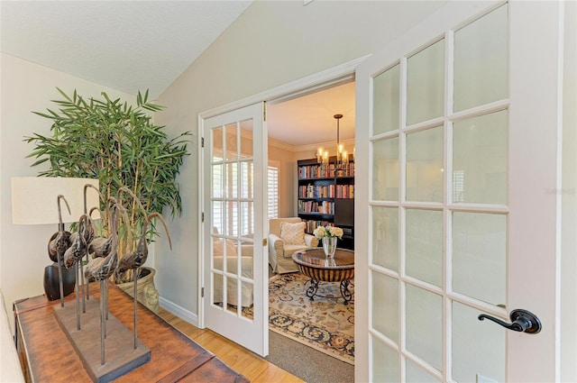 doorway with vaulted ceiling, a notable chandelier, wood finished floors, and french doors