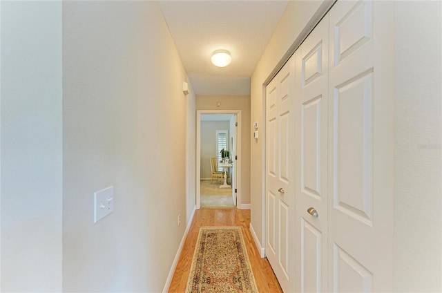 corridor featuring baseboards and light wood-style flooring