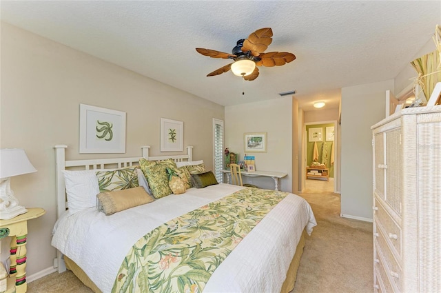 bedroom featuring a ceiling fan, light colored carpet, baseboards, and a textured ceiling