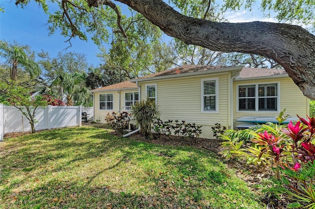 back of house featuring a lawn and fence