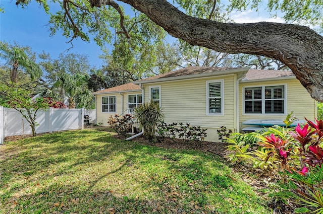 rear view of property with a lawn and fence