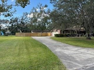 view of community featuring concrete driveway and a yard