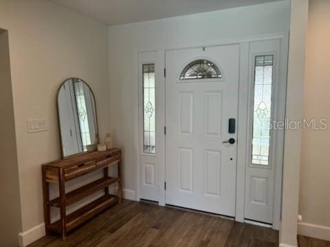 entryway with dark wood finished floors and baseboards