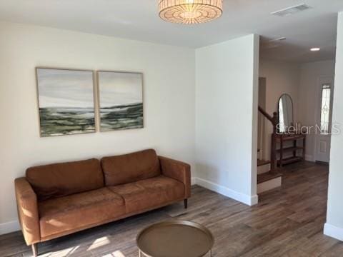 living area featuring visible vents, baseboards, wood finished floors, and stairway