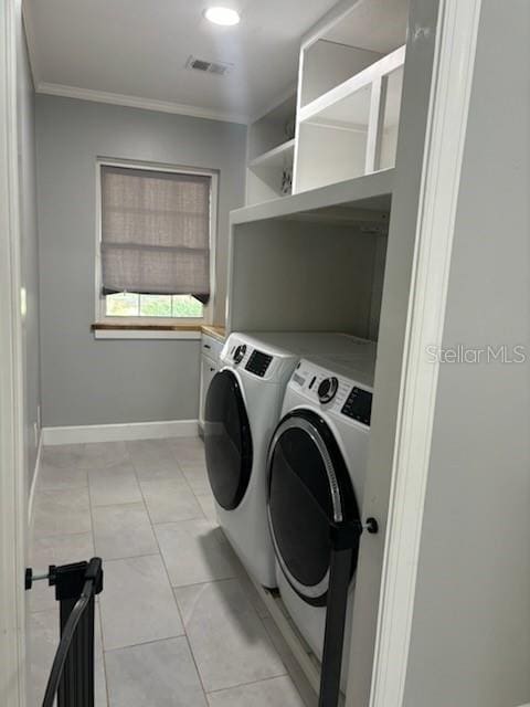 clothes washing area featuring visible vents, washing machine and dryer, crown molding, baseboards, and laundry area