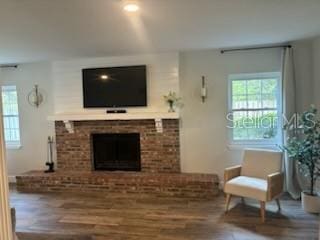 living area with a brick fireplace and wood finished floors