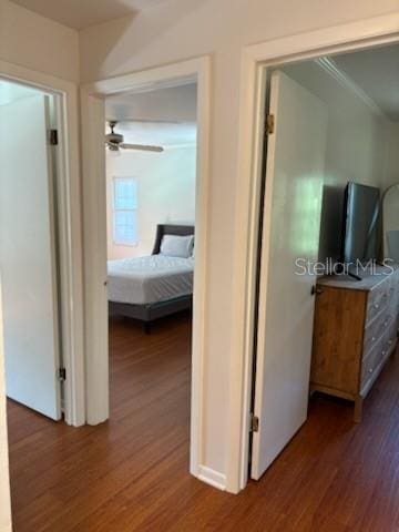 corridor with wood finished floors and ornamental molding