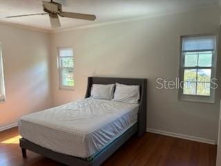 bedroom with multiple windows, wood finished floors, and baseboards