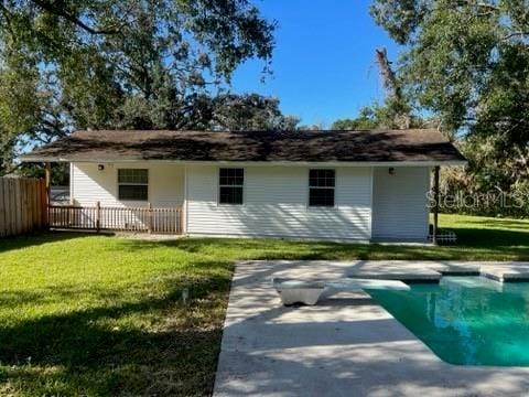 back of property featuring a fenced in pool, a patio, a yard, and fence