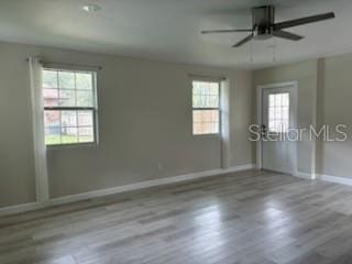 empty room featuring wood finished floors, a ceiling fan, and baseboards