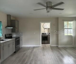 kitchen with light wood-type flooring, stainless steel electric range, wall chimney exhaust hood, stove, and ceiling fan