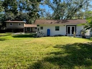 rear view of property with french doors and a lawn