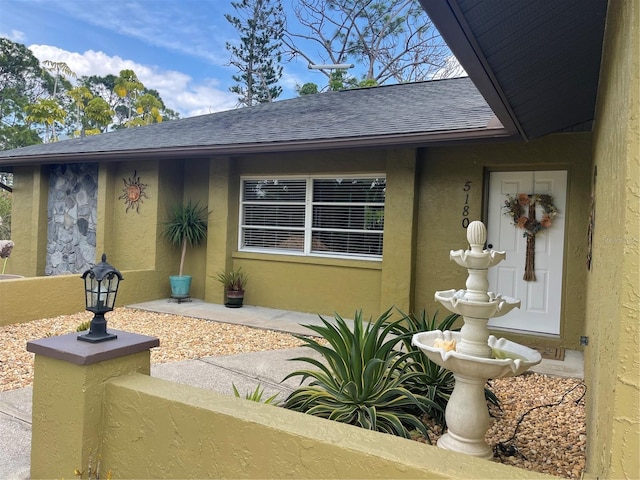 exterior space featuring stucco siding and roof with shingles