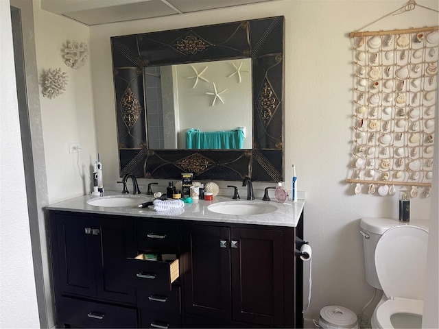 bathroom with double vanity, toilet, and a sink