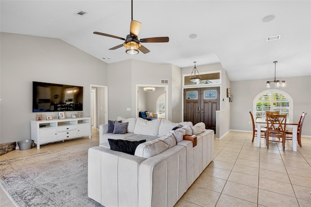 living area with light tile patterned floors, visible vents, lofted ceiling, and ceiling fan with notable chandelier