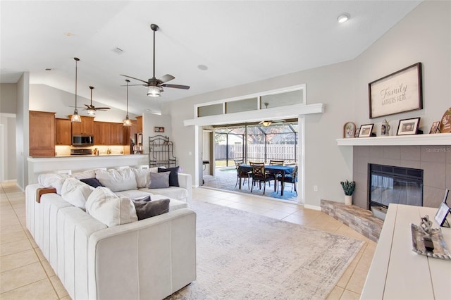 living room with visible vents, vaulted ceiling, a fireplace, light tile patterned flooring, and a ceiling fan