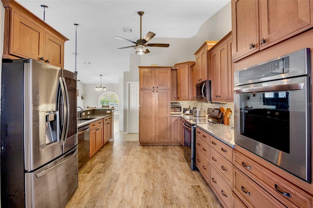 kitchen with a sink, stainless steel appliances, light wood-type flooring, and decorative backsplash