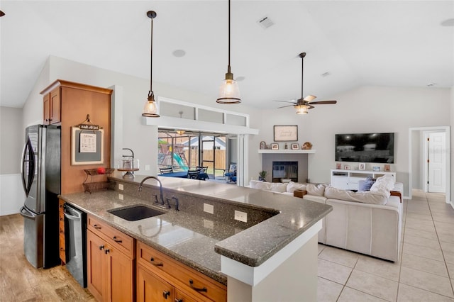 kitchen featuring a sink, vaulted ceiling, a peninsula, freestanding refrigerator, and stainless steel dishwasher