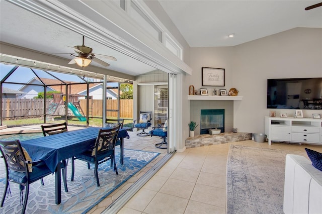 interior space featuring glass enclosure, fence, outdoor dining area, ceiling fan, and a tile fireplace