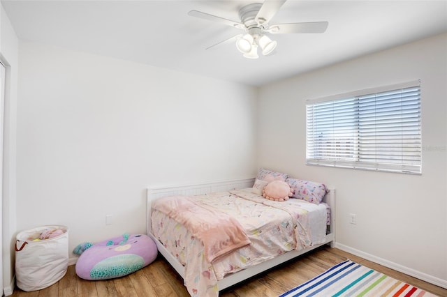 bedroom featuring baseboards, wood finished floors, and a ceiling fan