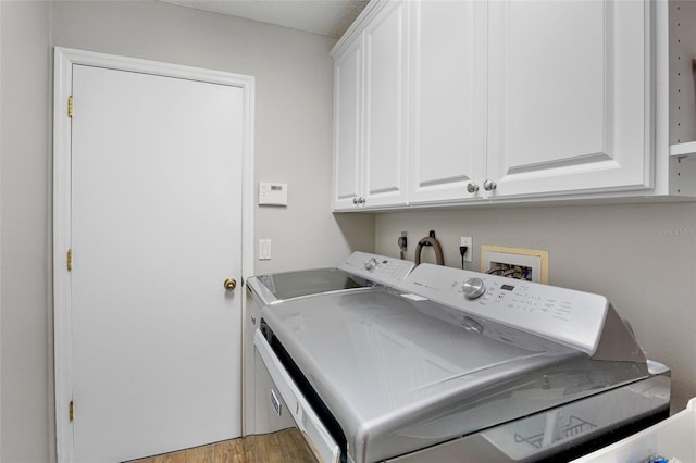 washroom with cabinet space, light wood-style flooring, and separate washer and dryer