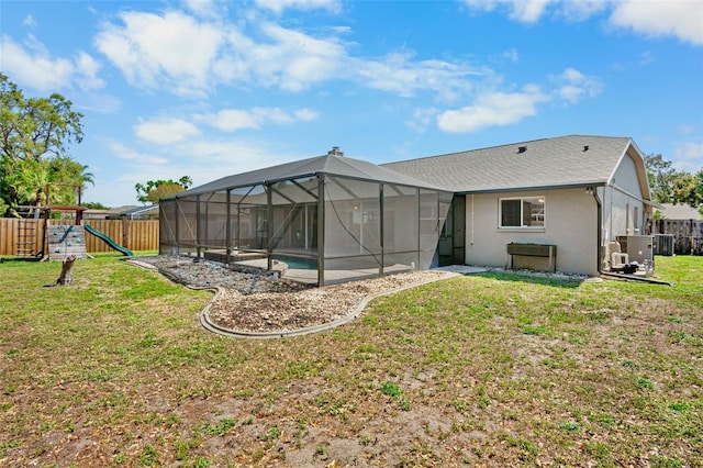 back of house featuring a fenced in pool, a playground, glass enclosure, a lawn, and a fenced backyard