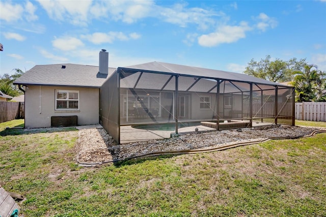 back of house with a yard, glass enclosure, a chimney, and a fenced backyard