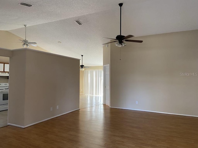 empty room featuring a textured ceiling, wood finished floors, ceiling fan, and vaulted ceiling