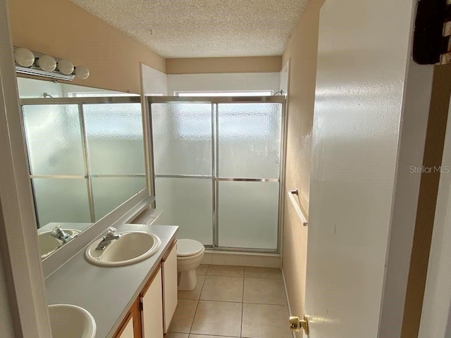 full bath featuring a sink, tile patterned flooring, a shower stall, a textured ceiling, and toilet