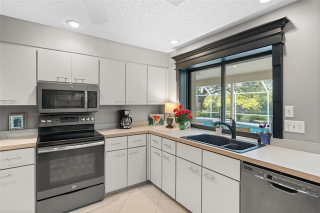 7300 Wax Myrtle Way, Sarasota, FL 34241 - kitchen with appliances with stainless steel finishes, a textured ceiling, light countertops, white cabinets, and light tile patterned floors