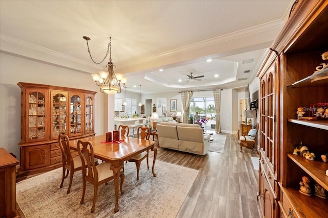 4691 Claremont Park Dr, Bradenton, FL 34211 - dining area featuring crown molding, wood finished floors, a ceiling fan, a chandelier, and a raised ceiling