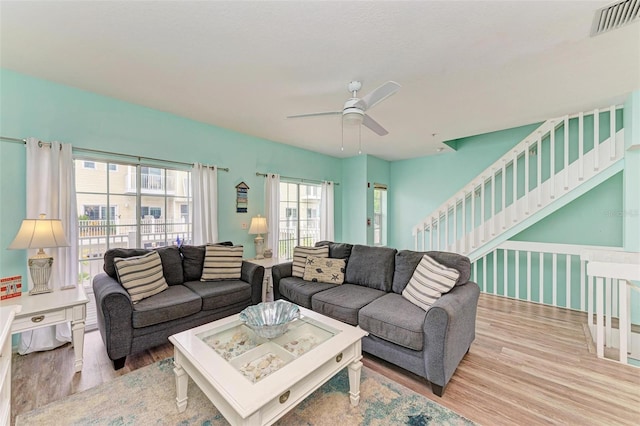 living area with visible vents, stairway, ceiling fan, and wood finished floors