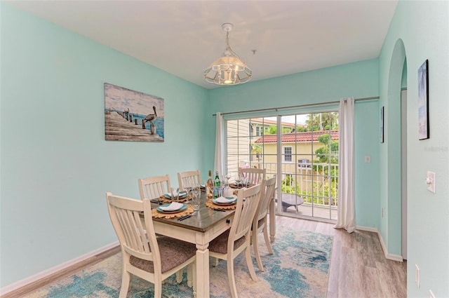 dining space featuring light wood finished floors, arched walkways, and baseboards