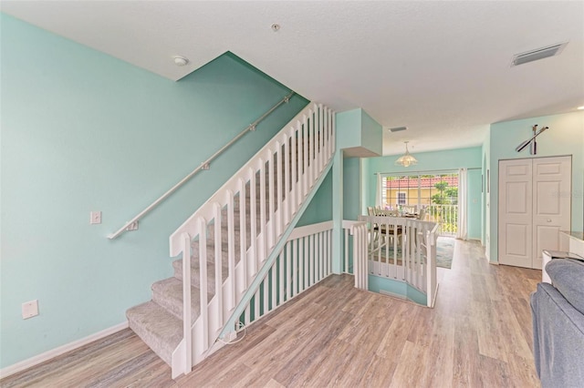 stairway with wood finished floors, visible vents, and baseboards