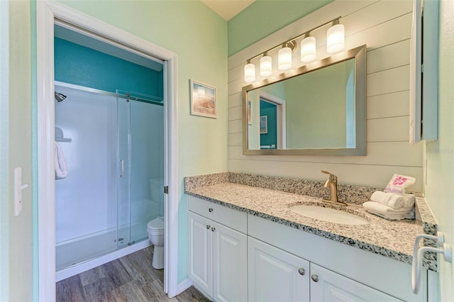 full bath featuring a shower stall, toilet, vanity, and wood finished floors