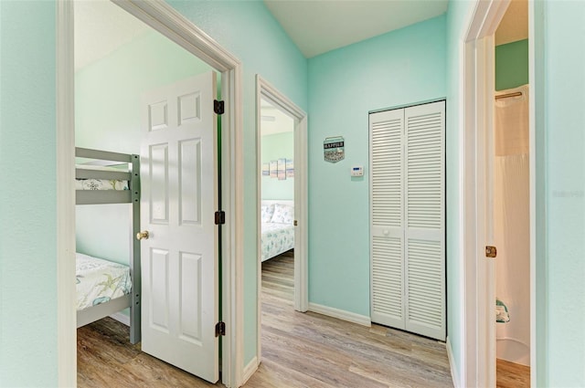 corridor featuring baseboards and light wood finished floors